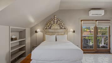 A bedroom with a large bed, a decorative headboard, two wall-mounted lamps, and a sliding glass door leading to an outdoor area.