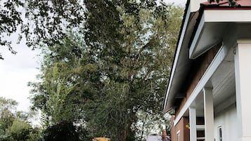 A pathway leading to a building with a covered porch and a gravel driveway.
