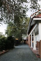 A pathway leading to a building with a covered porch and a gravel driveway.