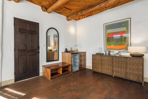 A room with a wooden door, a bench, a mirror, a cabinet, and a large abstract painting. - The Parador (Santa Fe)