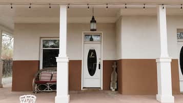 A building with a white and brown facade, a porch with white columns, a door with a glass panel, and a hanging lantern.