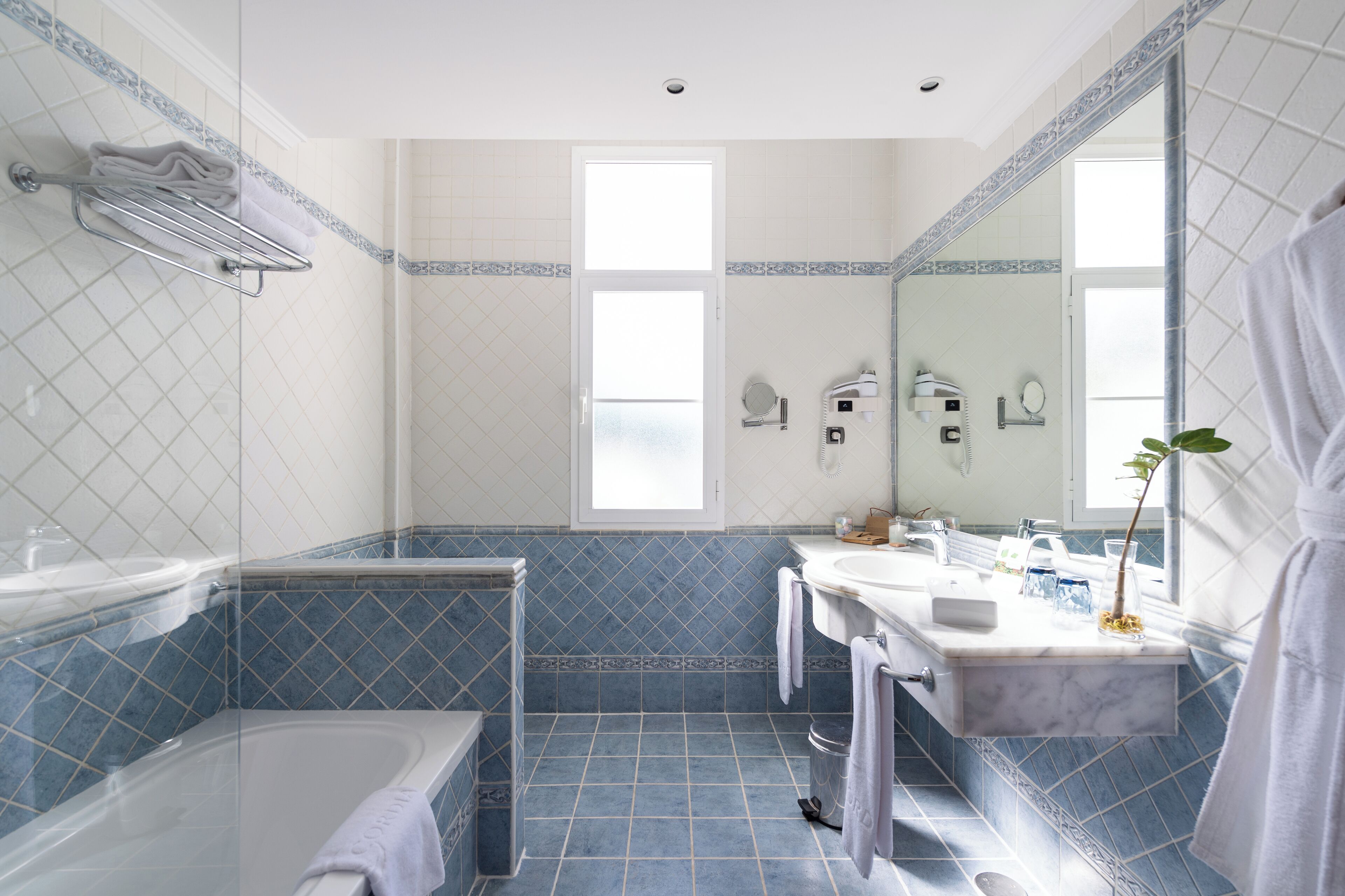 A modern bathroom with a bathtub, two sinks, a large mirror, and a shower.