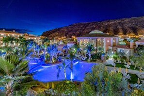 A resort with a swimming pool, palm trees, and a mountain backdrop. - Hotel Cordial Mogán Playa (Mogan)