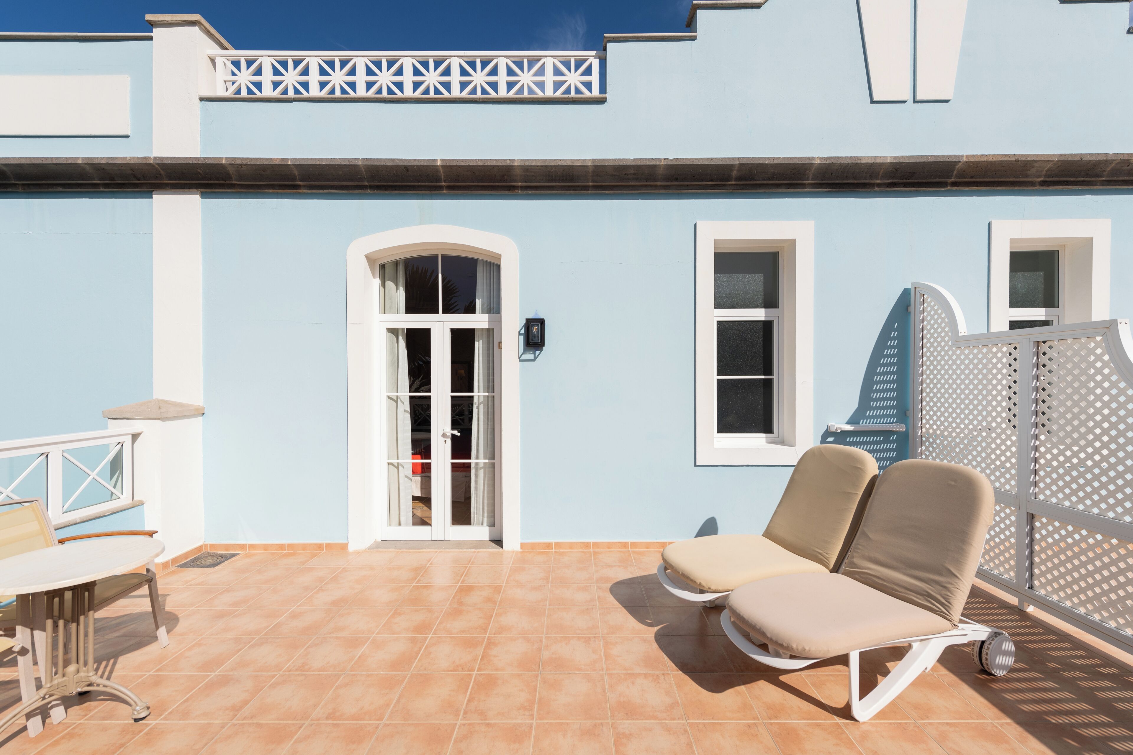 A blue building with a tiled patio, a white door, and a window.