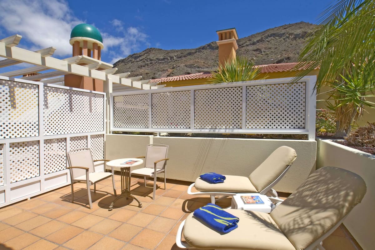 Un espace extérieur ensoleillé, aménagé avec une pergola, des chaises et une table.