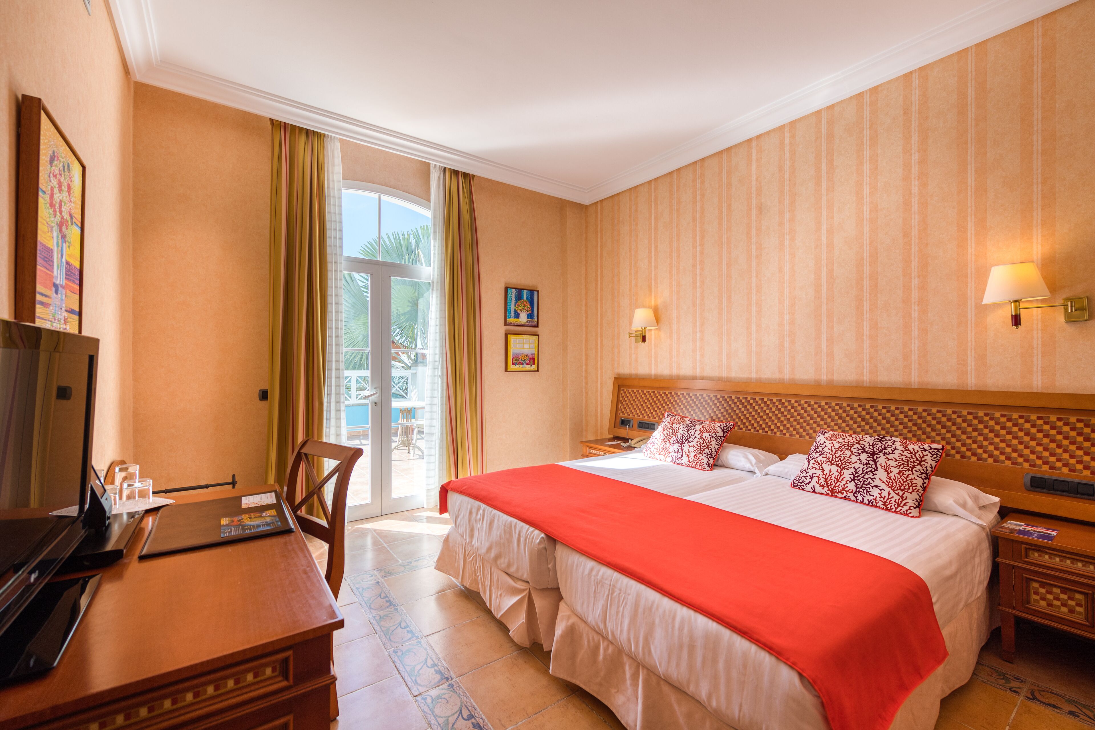 A hotel room with a large bed, a desk, a television, and a view of the outdoors.