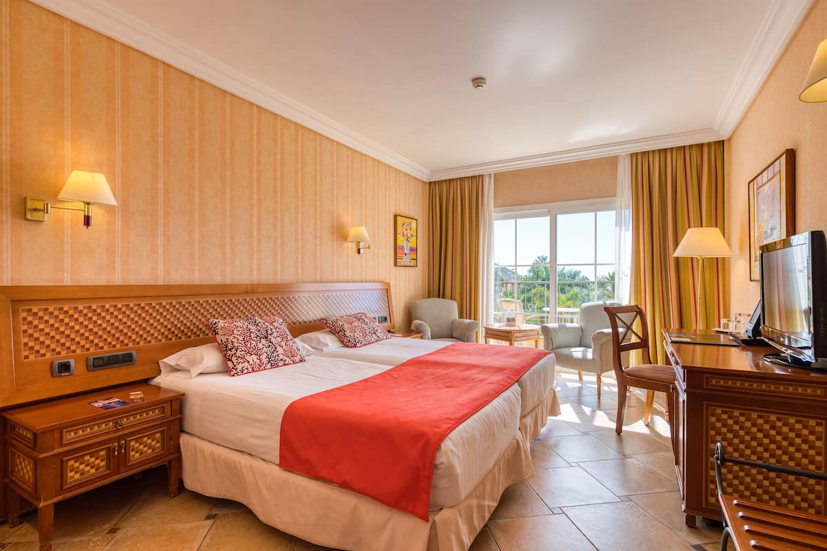 Une chambre d’hôtel avec deux lits, une télévision, un bureau et une vue sur l’extérieur.