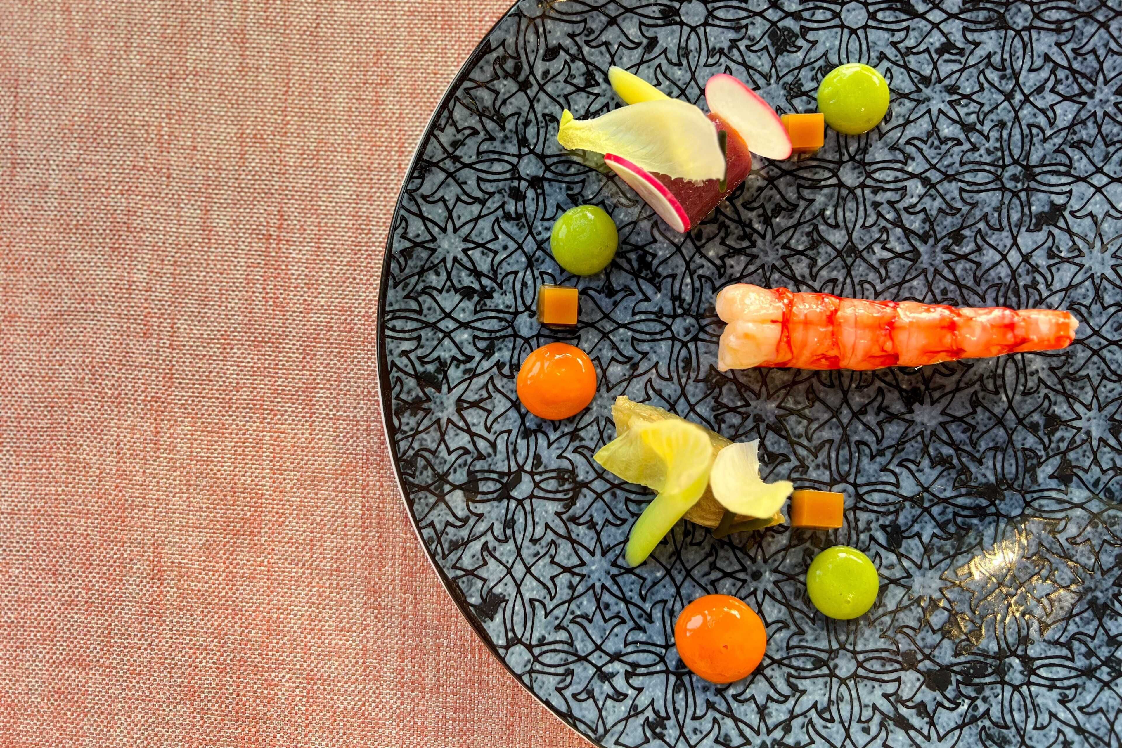 Un plato con diversas frutas y verduras, como zanahoria, uvas y una rebanada de manzana.