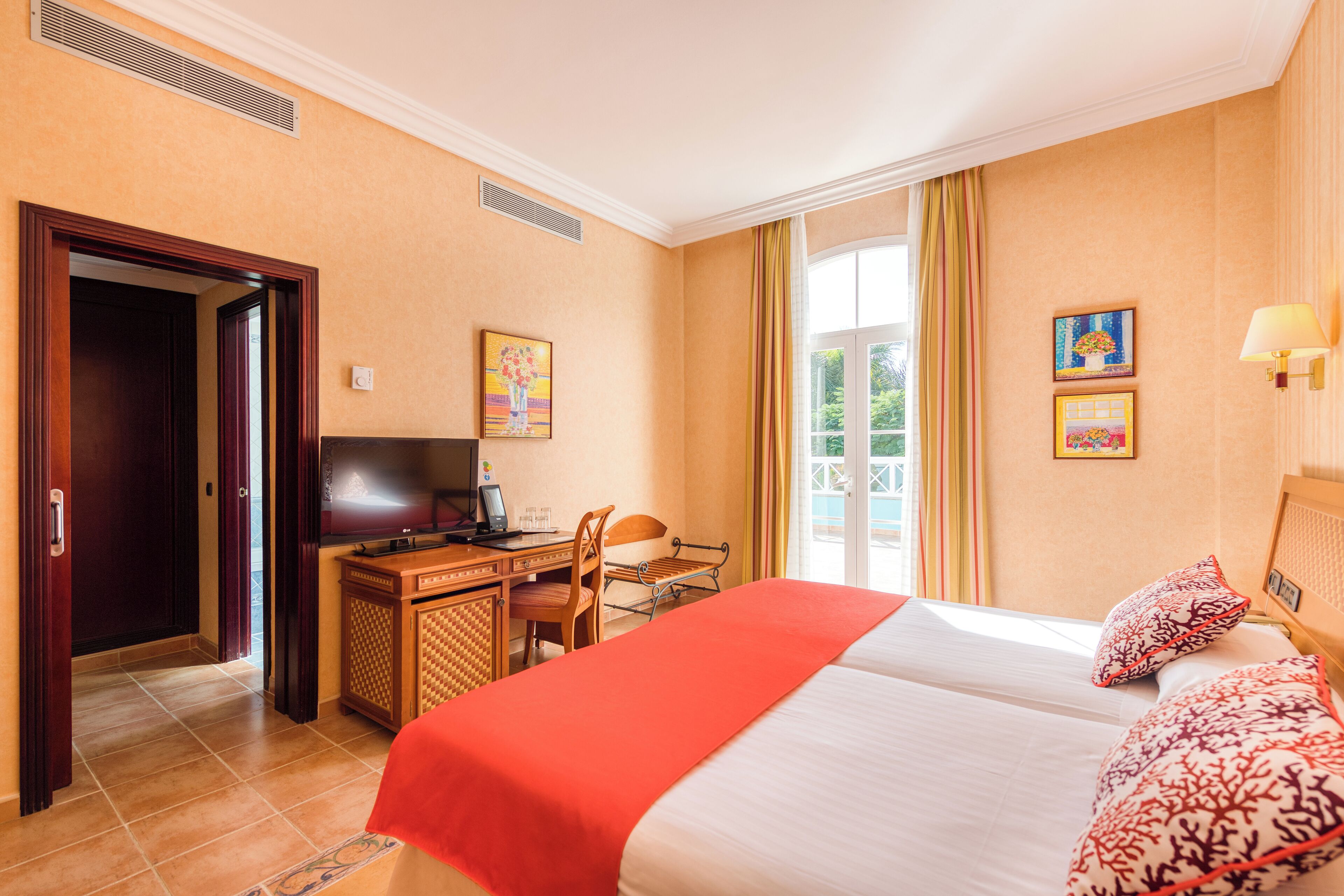 Habitación de hotel con cama, escritorio, silla y televisor.