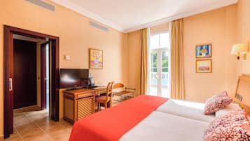Habitación de hotel con cama, escritorio, silla y televisor.