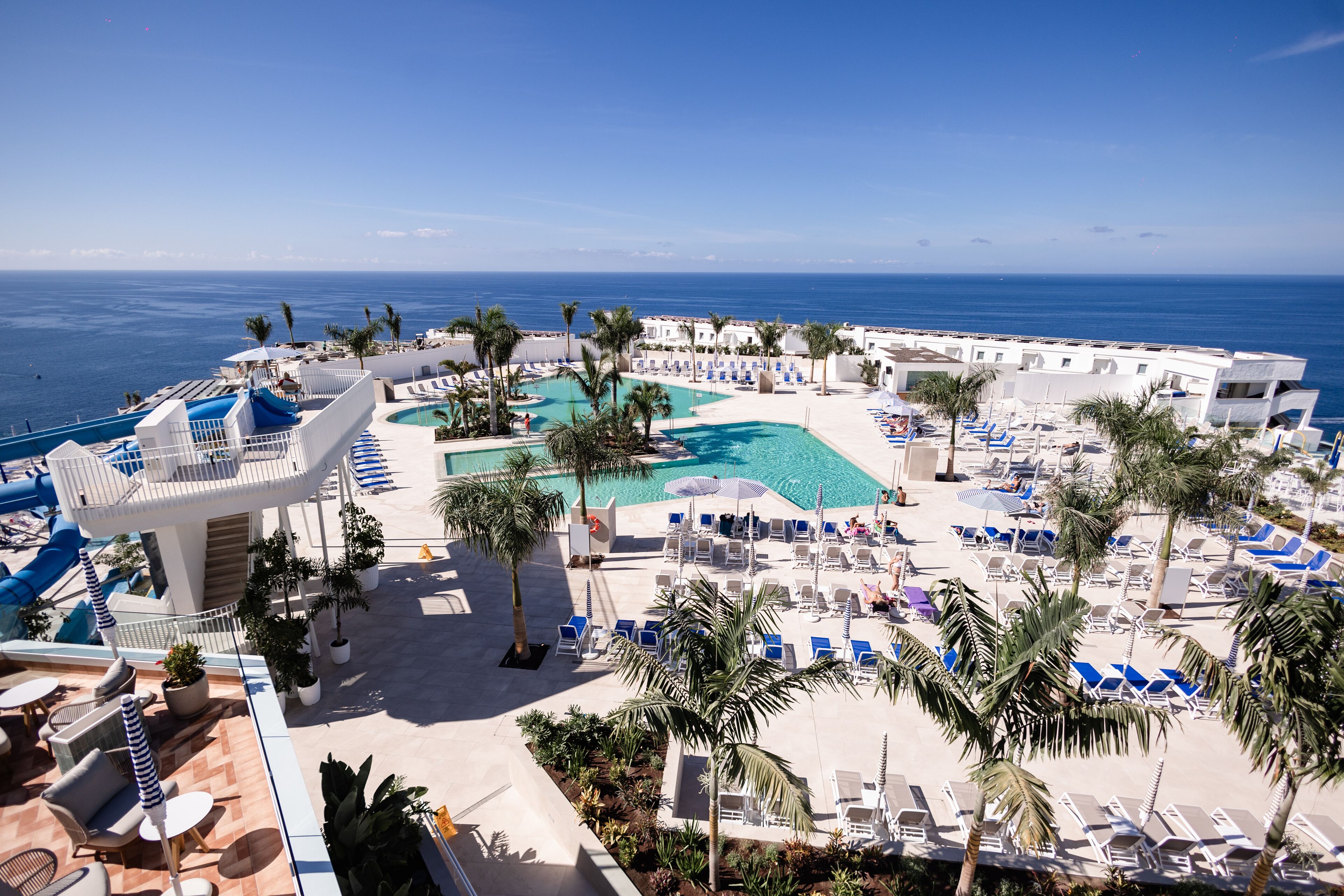 A resort with a pool area, lounge chairs, and palm trees.