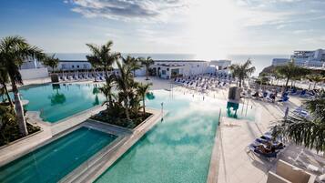 Relax by the ocean with a clear view from our infinity pool, surrounded by lounge chairs and palm trees.