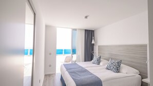 A modern hotel room with a large bed, a view of the sea, and a balcony. - Servatur Puerto Azul (Mogan)