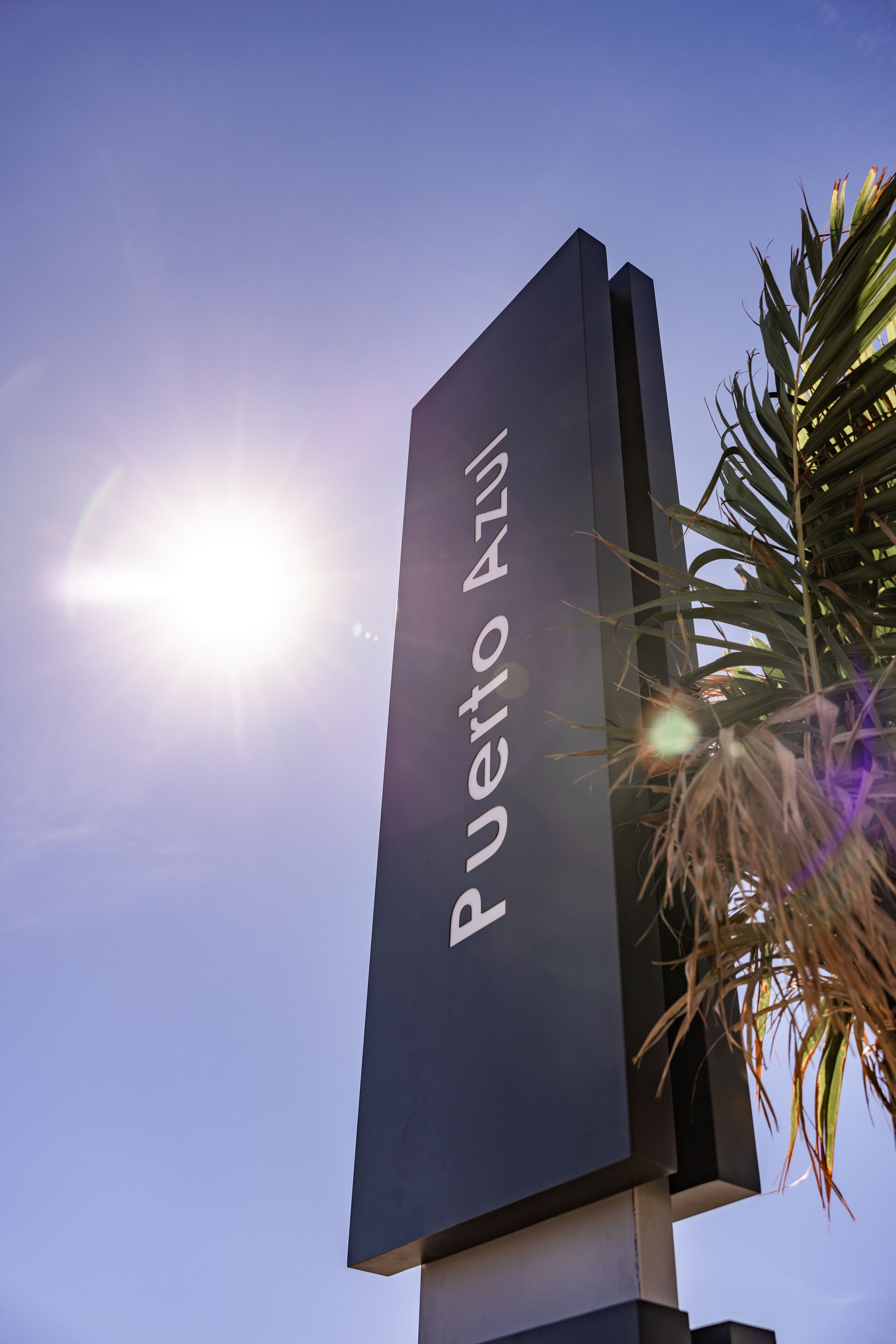 Uma placa com o texto 'Puerto Rico' contra um céu azul com o sol brilhando.