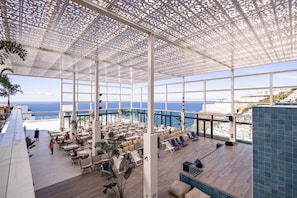 A spacious indoor area with a high ceiling and large windows overlooking the sea. - Servatur Puerto Azul (Mogan)