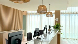 A modern reception area with a long counter, multiple computer monitors, and a potted plant. - Servatur Puerto Azul (Mogan)