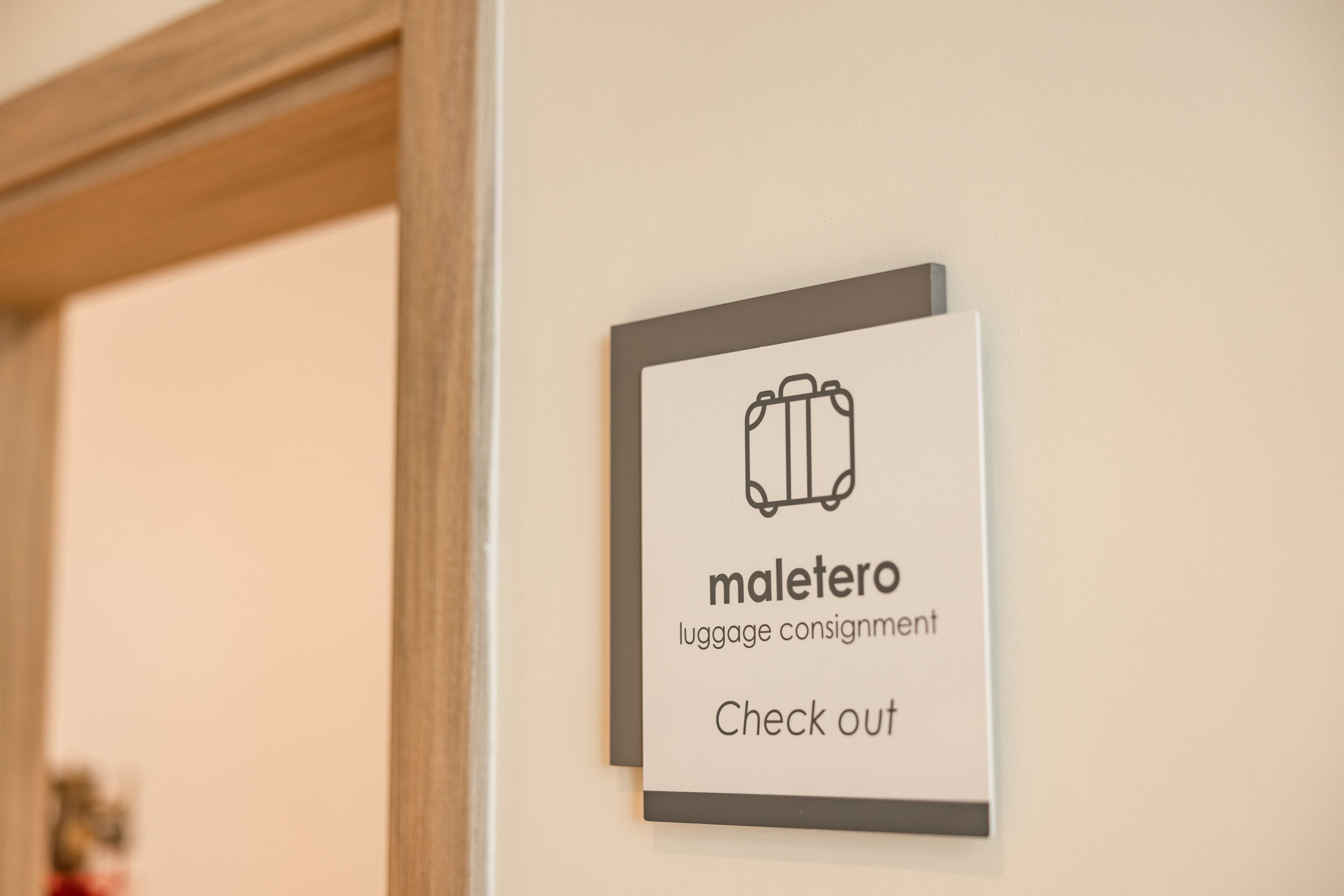 Señal que indica un área de consigna de equipaje, con un icono de maleta y el texto 'maletero check out'.