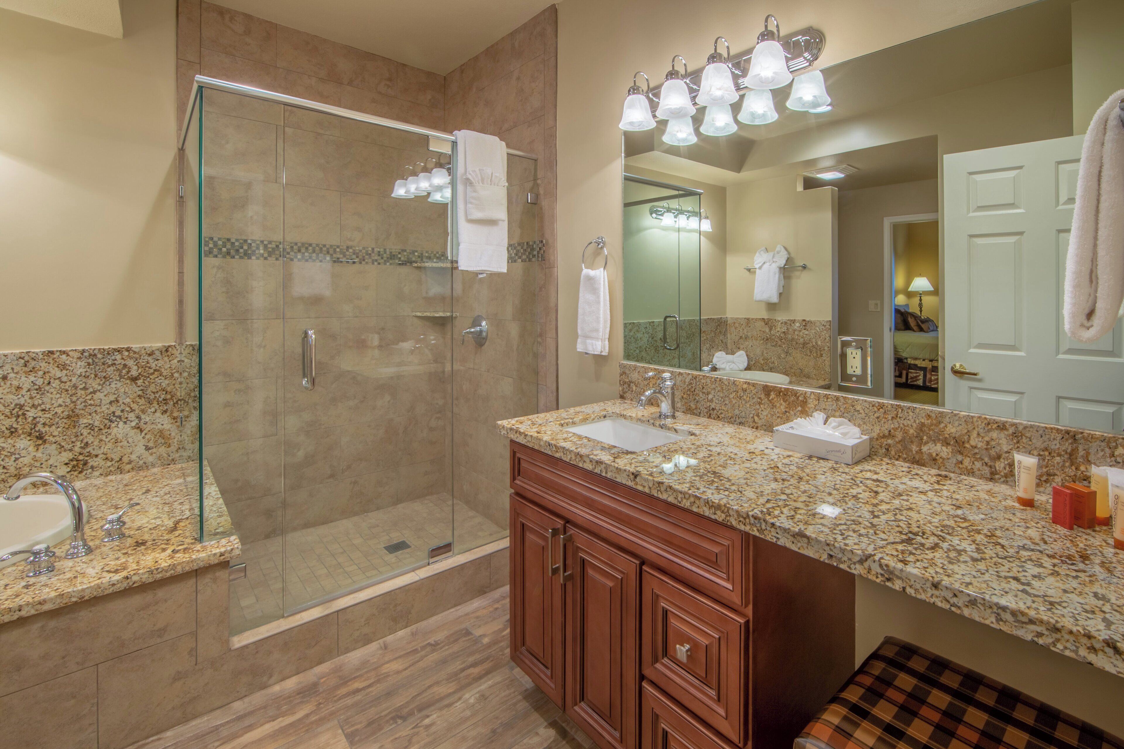 A modern bathroom with a glass-enclosed shower, a vanity with a sink, and a large mirror.