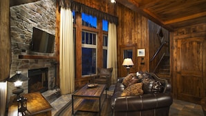 A cozy living room with a stone fireplace, leather sofa, and a staircase leading to another level. - Holiday Inn Club Vacations David Walley's Resort by IHG (Genoa)