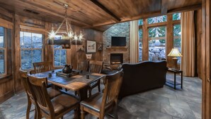 A rustic interior with a stone fireplace, wooden dining table, and chairs.