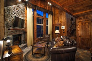 A cozy living room with a stone fireplace, leather sofa, and a staircase. - Holiday Inn Club Vacations David Walley's Resort by IHG (Genoa)