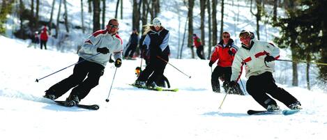 A group of people skiing on a snowy slope with trees in the background.