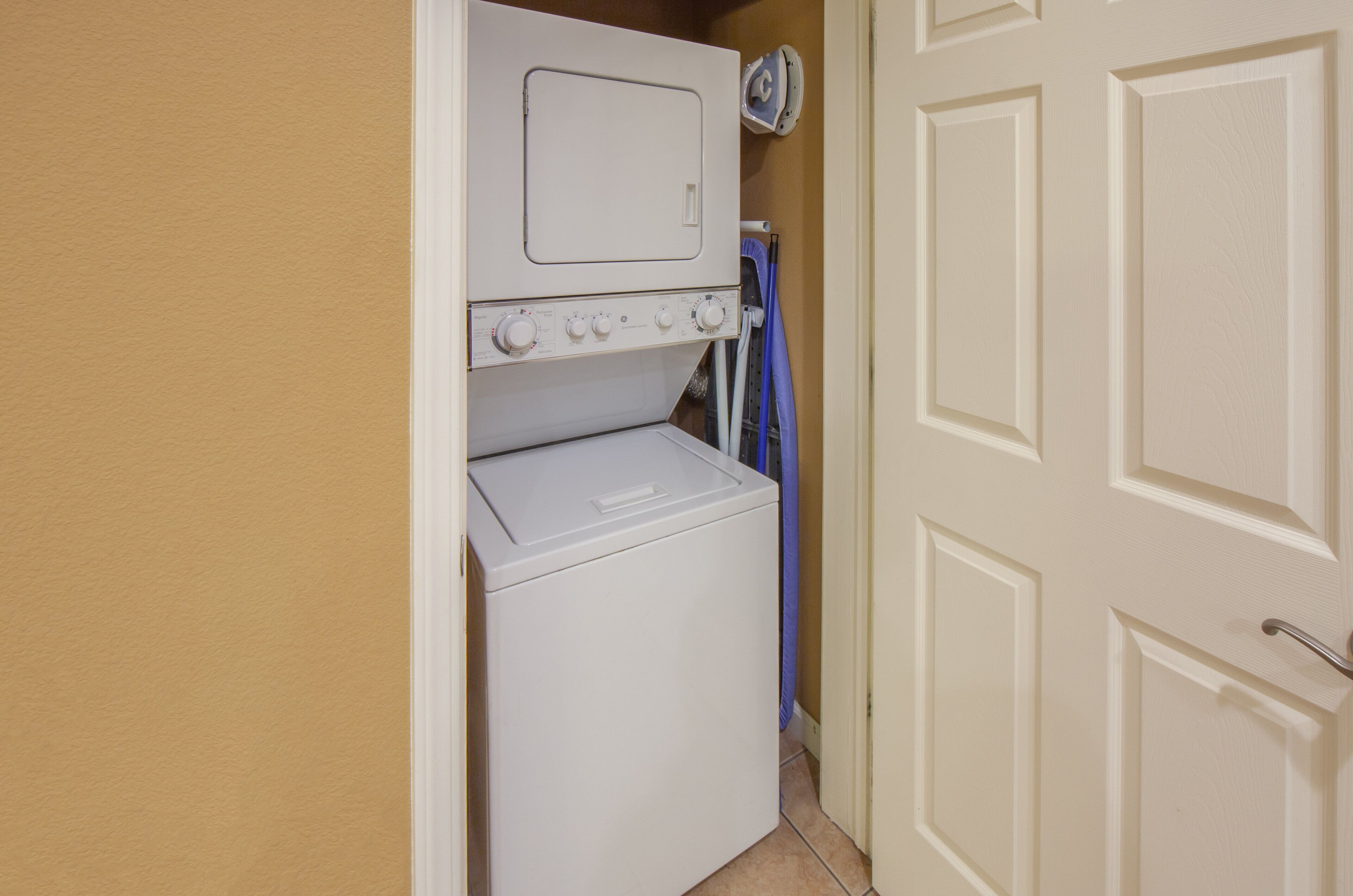 A compact laundry area with a washer and dryer, a blue towel rack, and a door with a handle.