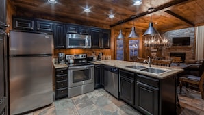 A modern kitchen with dark cabinetry, stainless steel appliances, and a stone tile floor. - Holiday Inn Club Vacations David Walley's Resort by IHG (Genoa)