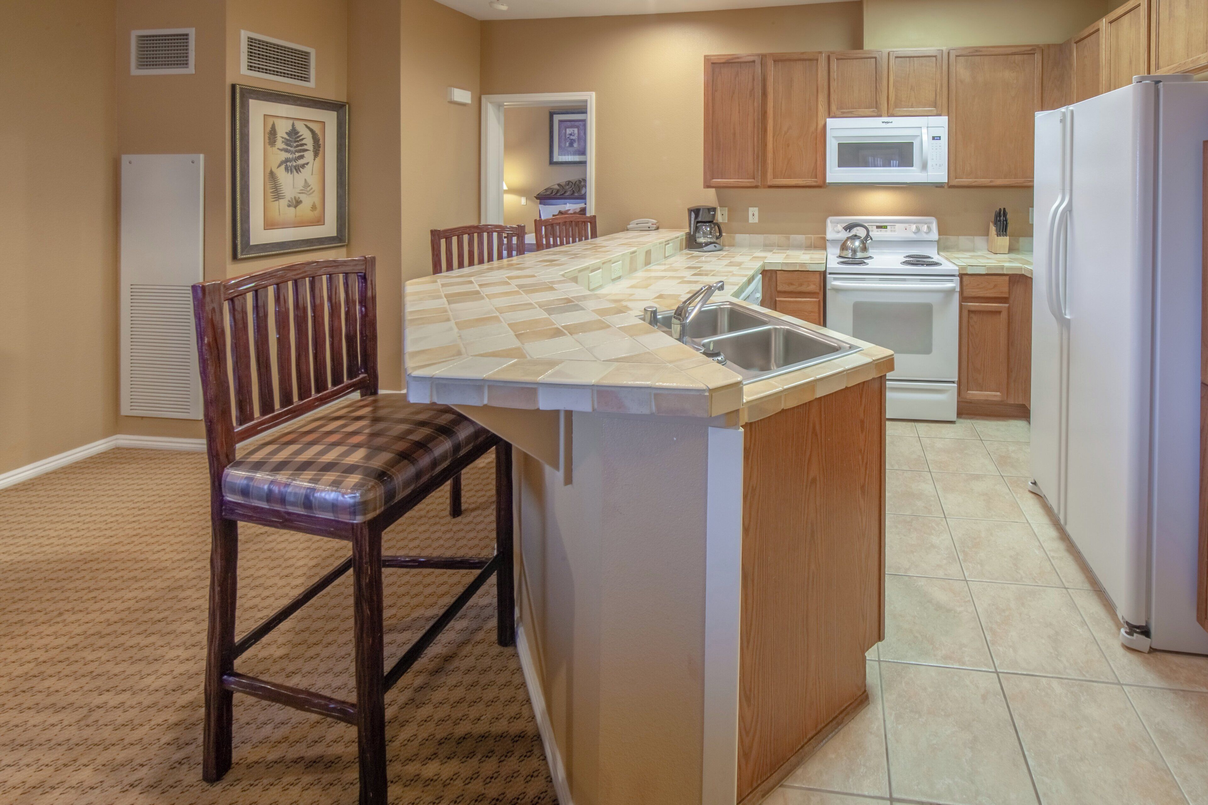 A kitchen with a central island, wooden cabinets, a microwave, stove, and a sink.