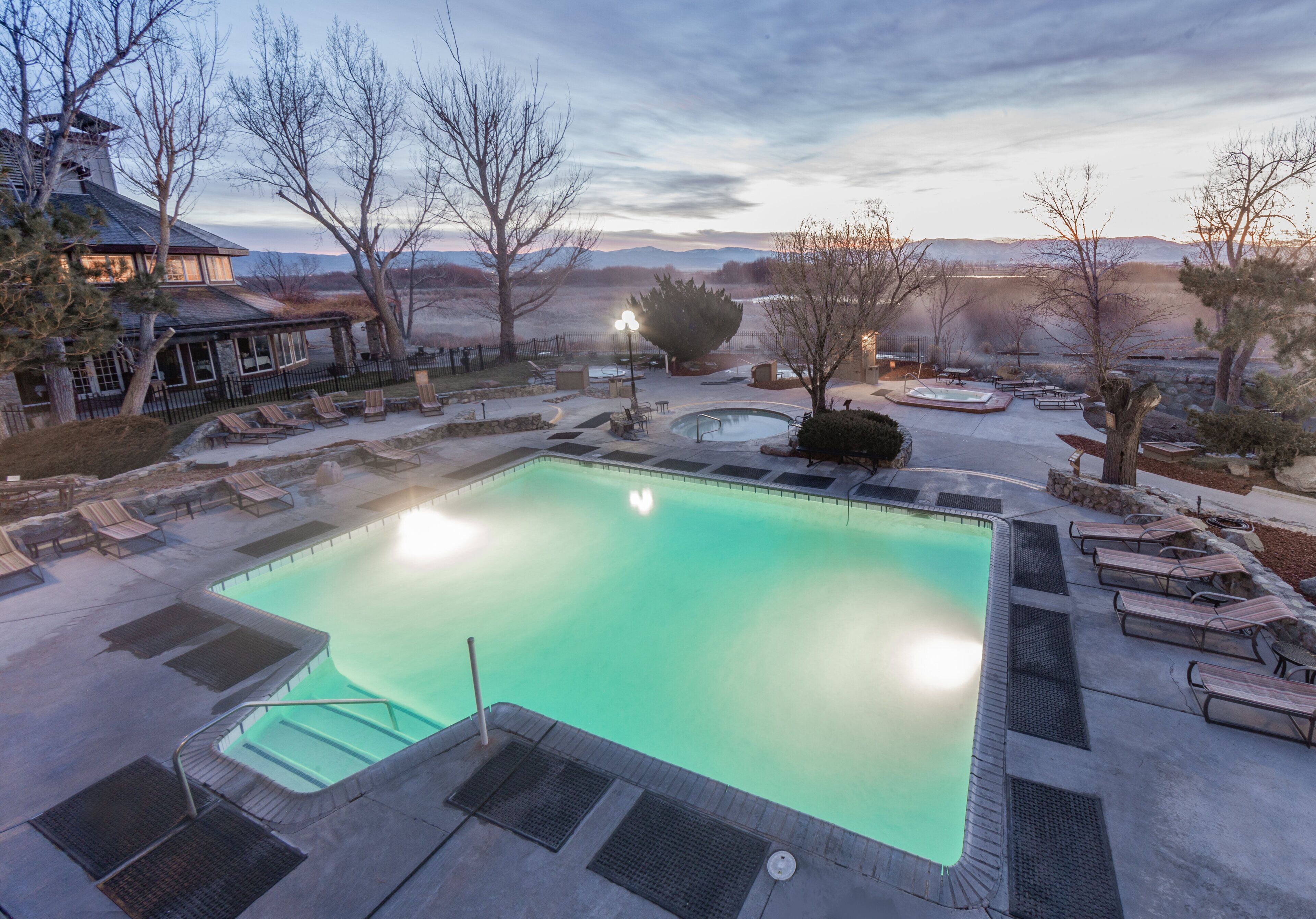 Une piscine dotée de chaises longues et d’un jacuzzi, entourée d’arbres et offrant une vue sur la montagne.