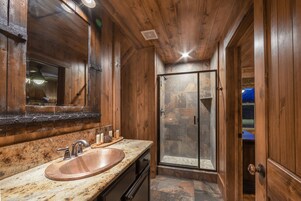 Un baño de madera con un lavamanos grande, un espejo y una ducha.