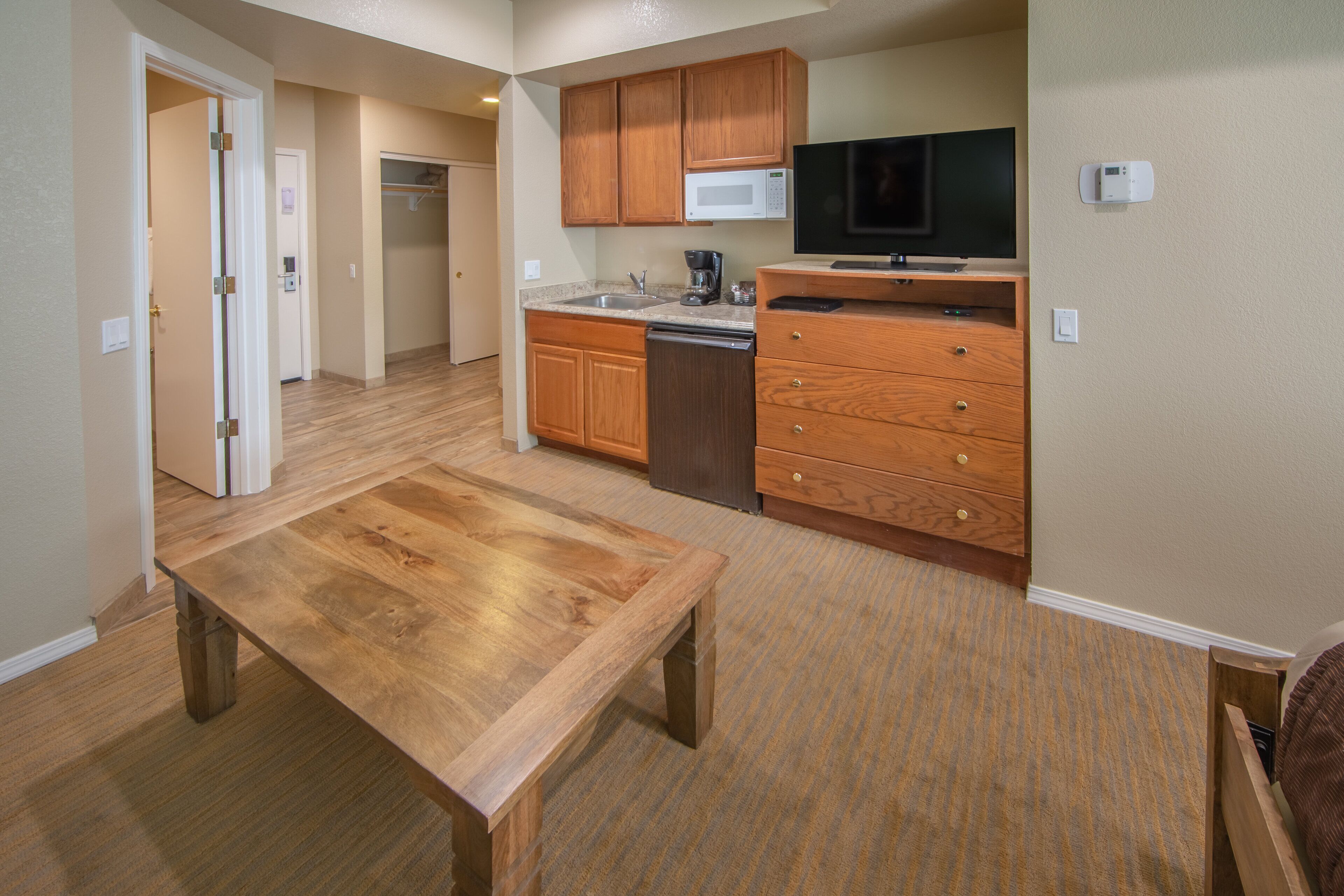 A compact kitchen with wooden cabinets, a microwave, a coffee maker, and a dishwasher.