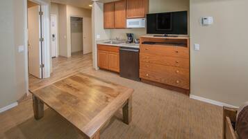 A compact kitchen with wooden cabinets, a microwave, a coffee maker, and a dishwasher.