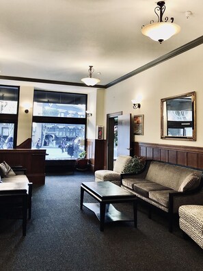 A spacious lobby with a large window, a sofa, a coffee table, and a mirror on the wall. - Hotel North Beach (San Francisco)