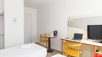 A hotel room with a bed, a desk with a laptop, a television, and a chair.
