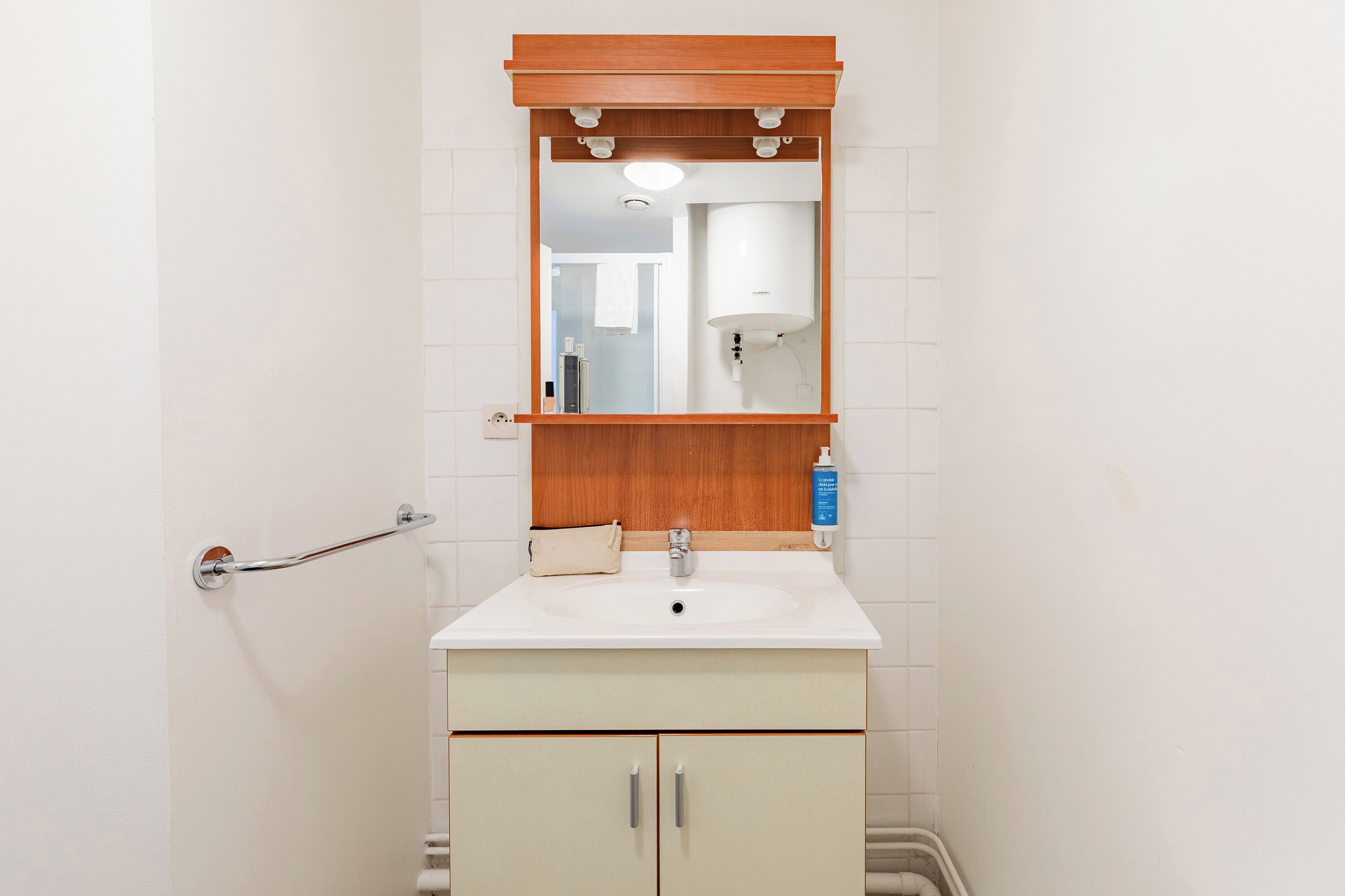 Une salle de bain avec un lavabo blanc, un meuble-lavabo en bois et un miroir au-dessus.