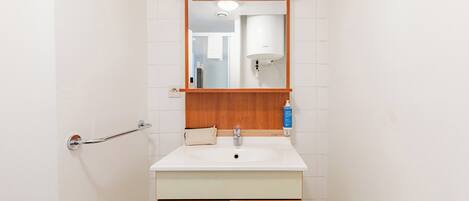 Une salle de bain avec un lavabo blanc, un meuble-lavabo en bois et un miroir au-dessus.