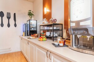 Un bar pour le petit-déjeuner équipé d’une machine à café, d’un panier de fruits et de divers aliments pour le petit-déjeuner.