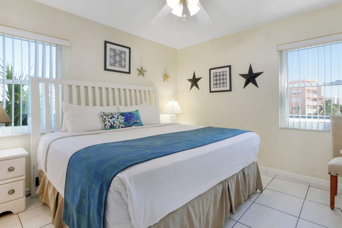 A bedroom with a bed, bedside tables, a window, and a door.