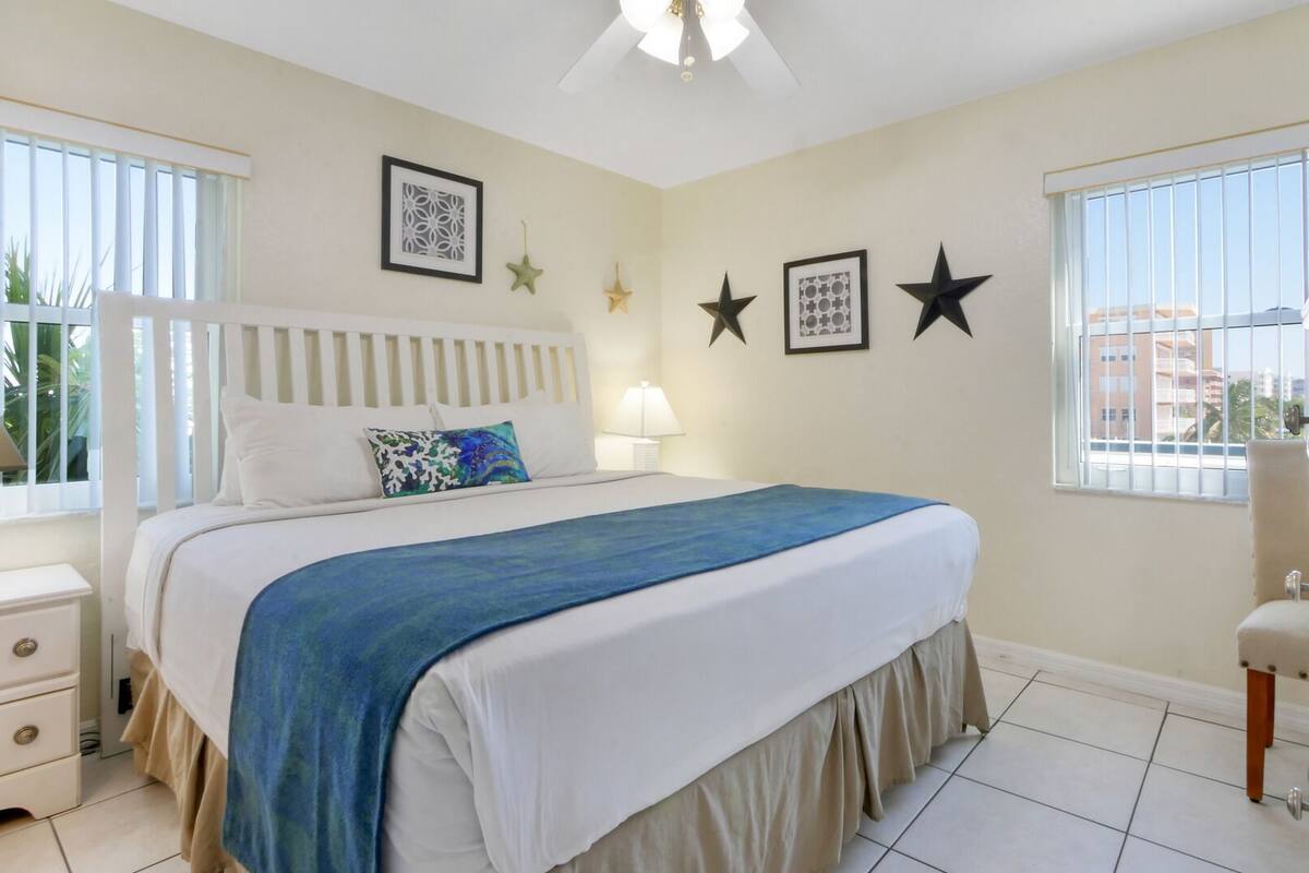 A bedroom with a bed, bedside table, lamp, and decorative wall art.