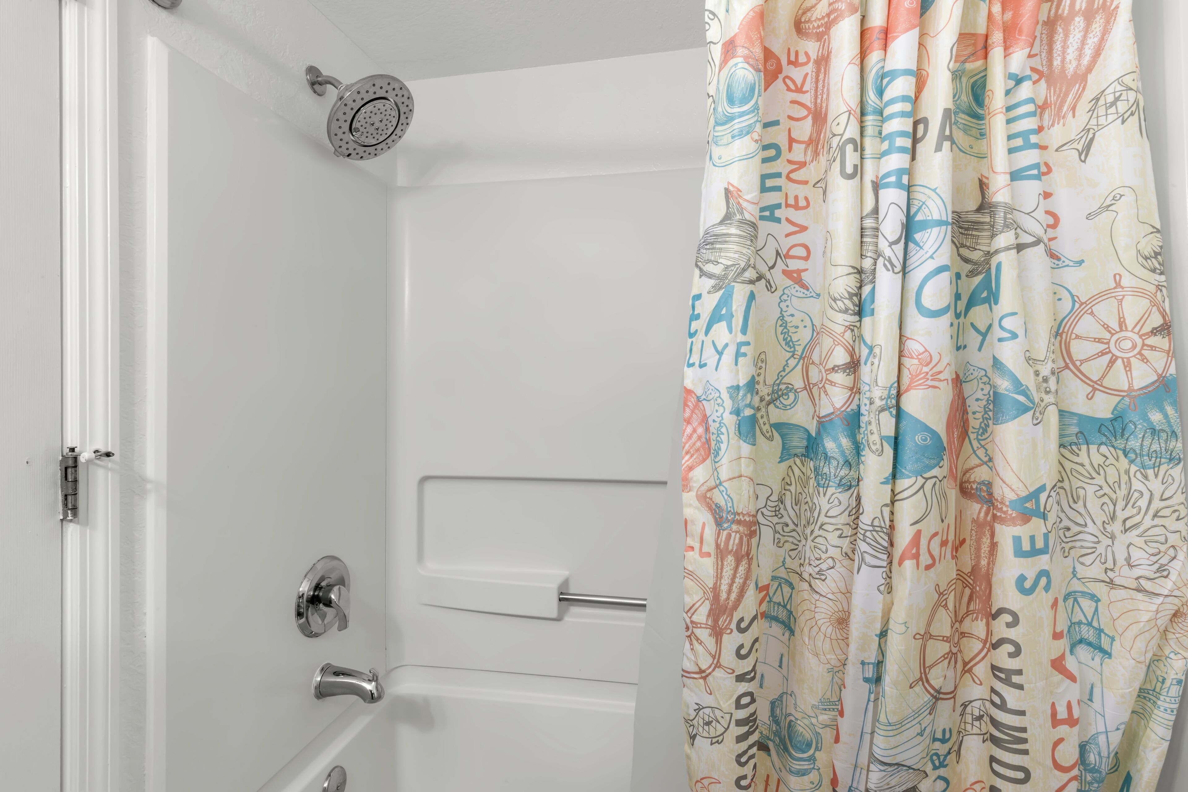 A bathroom with a shower curtain featuring nautical and travel-themed designs.
