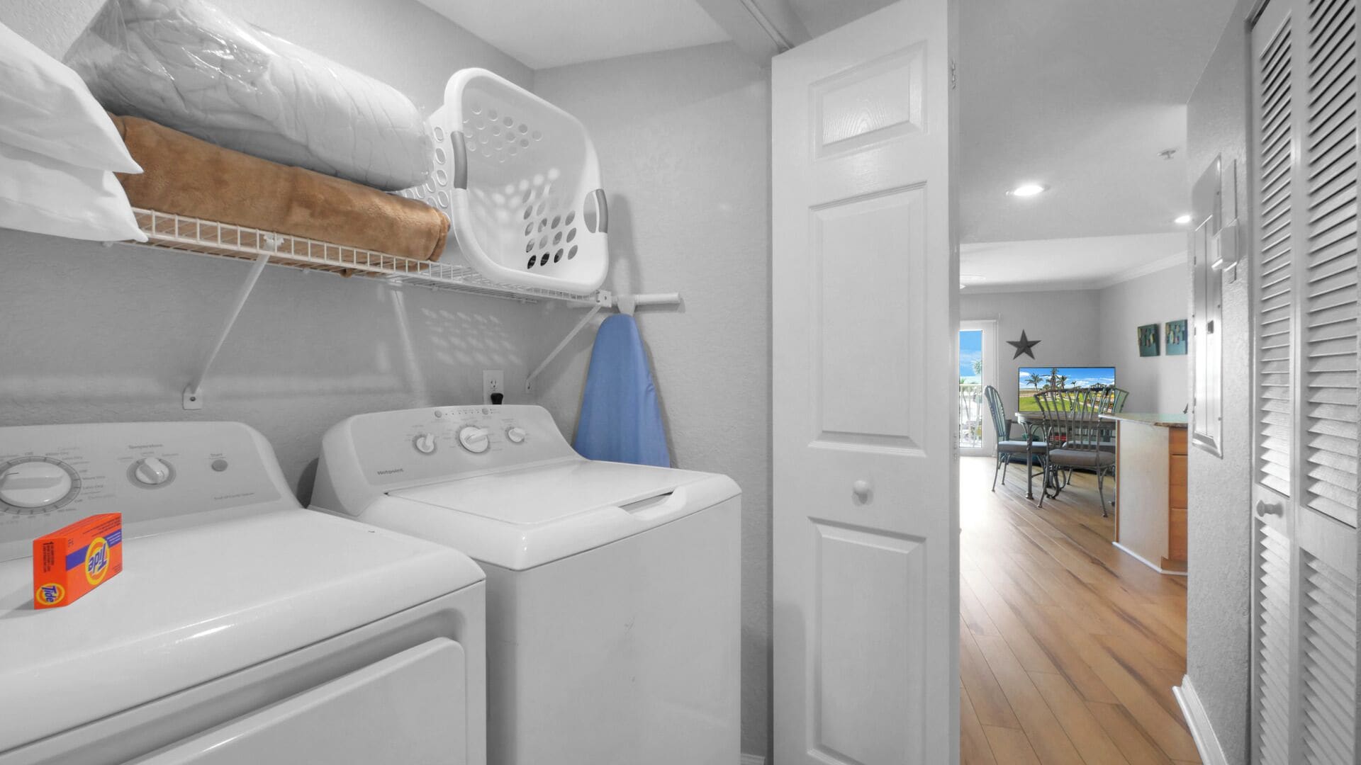 A laundry area with two white washing machines, a drying rack, and a blue drying cloth.