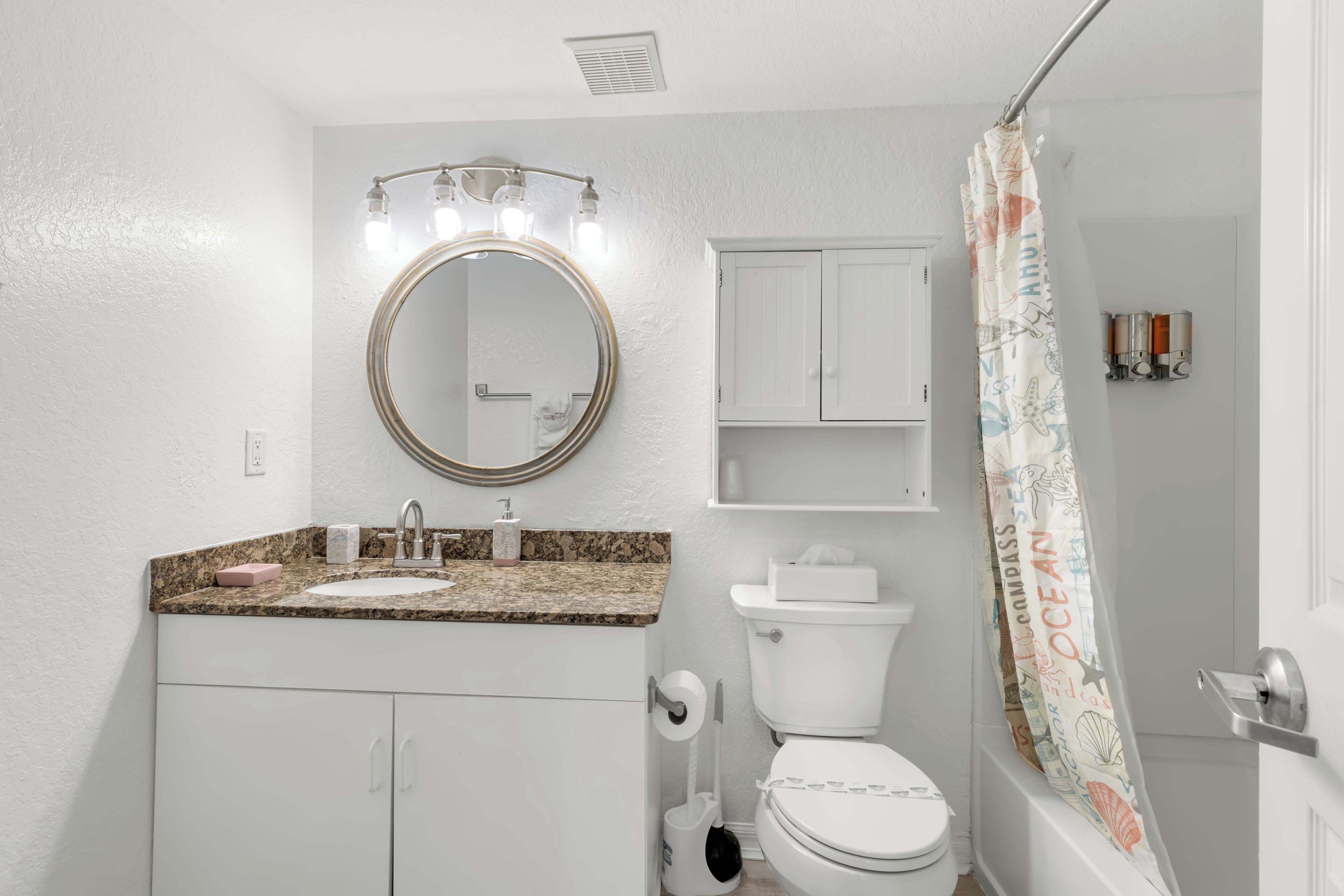 A bathroom with a sink, mirror, toilet, and shower curtain.