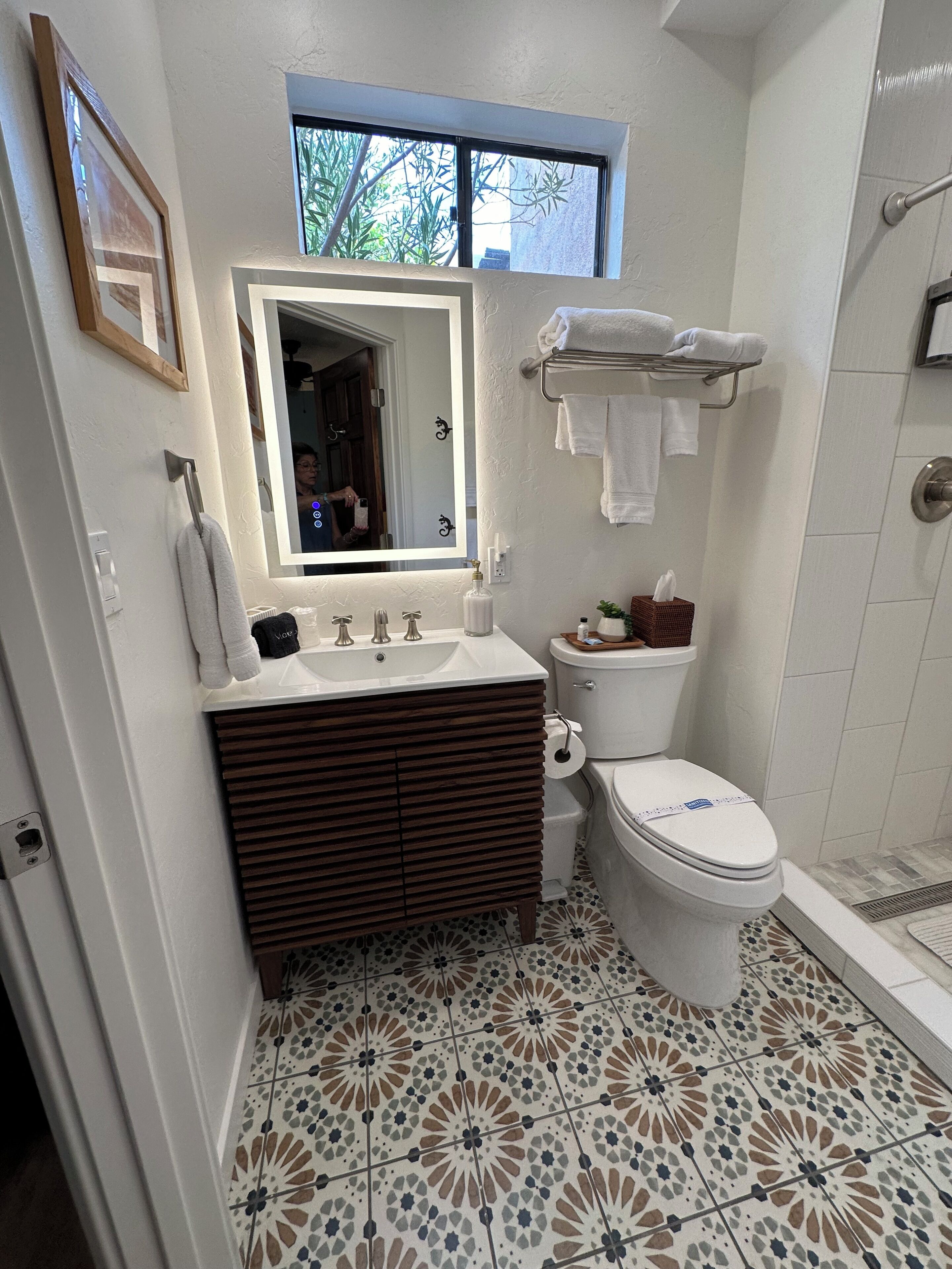 A bathroom with a vanity, sink, mirror, toilet, and shower.