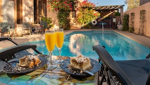A poolside setting with two plates of food and two glasses of orange juice. - Adobe Rose Inn B&B (Tucson)