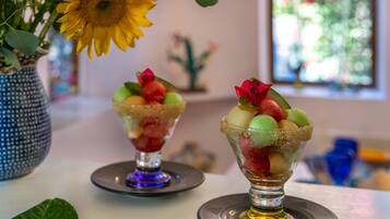 Two dessert glasses on a table with a vase of sunflowers and a decorative cactus in the background.
