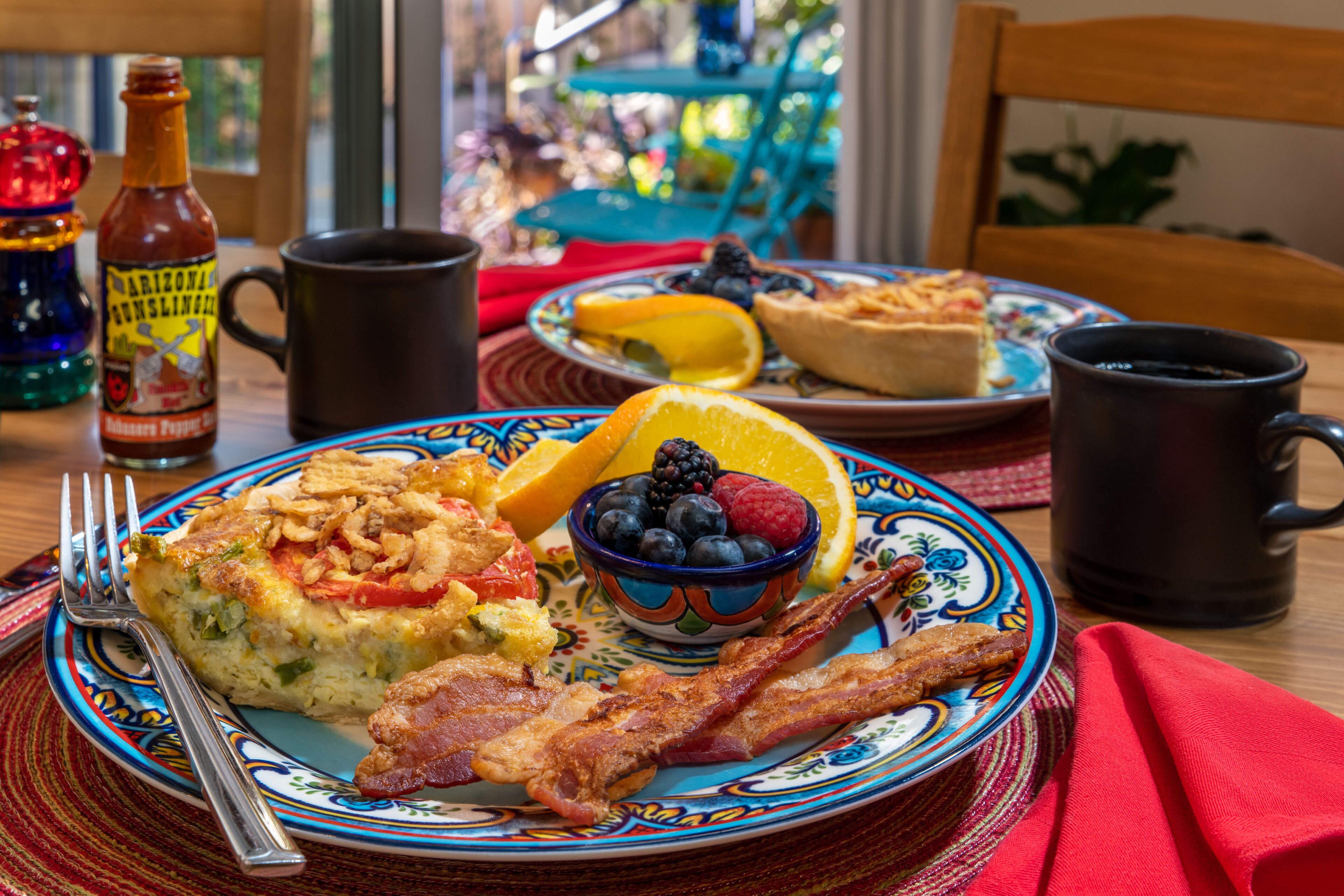 A breakfast plate with eggs, bacon, blueberries, and orange slices.