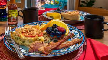 A breakfast plate with eggs, bacon, blueberries, and orange slices.