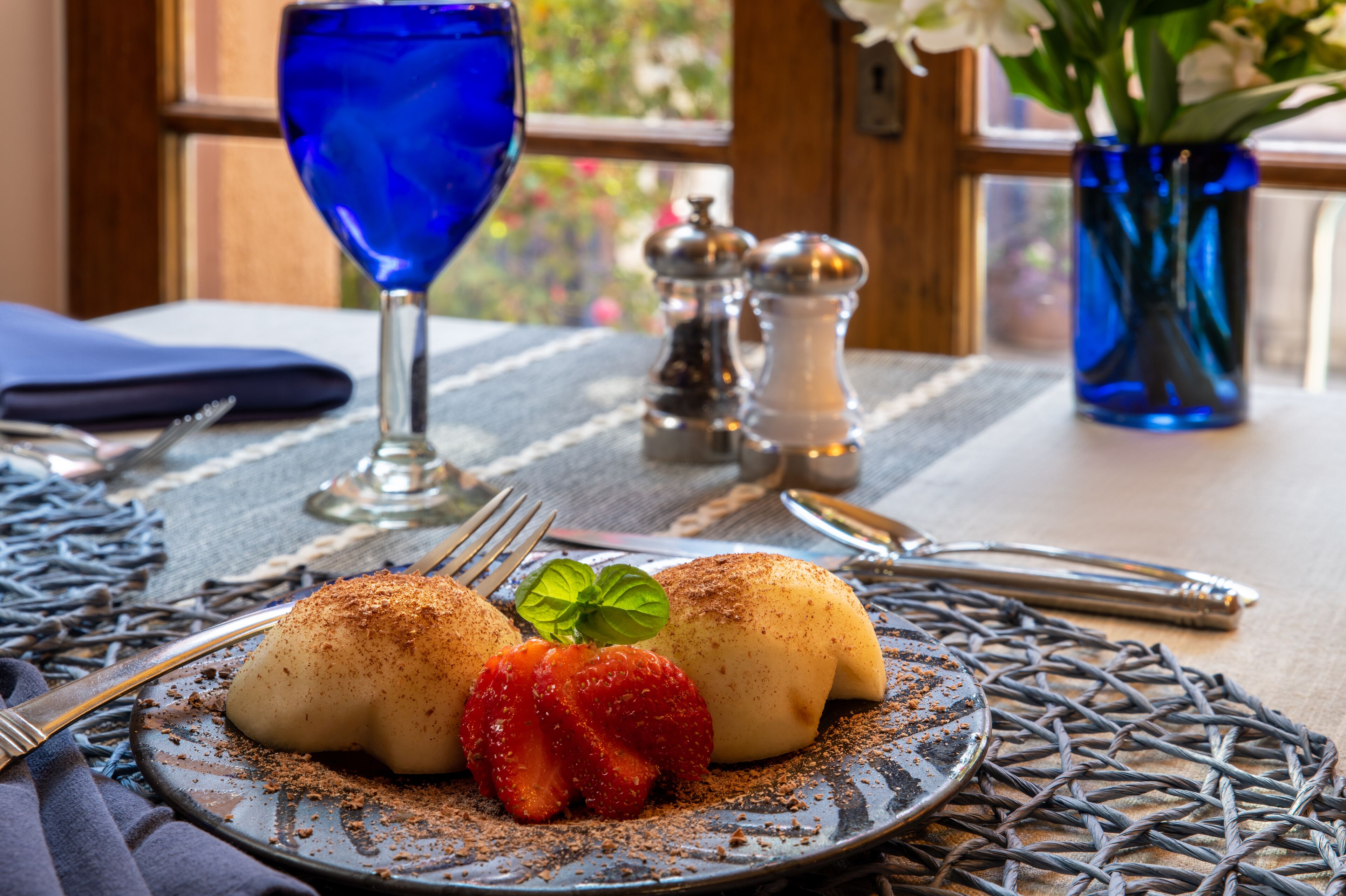 A plate with dumplings, a strawberry, and a blue glass.