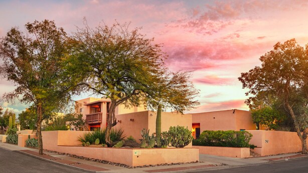 A residential building with a flat roof, a balcony, and a well-maintained garden with cacti and shrubs. - Adobe Rose Inn B&B (Tucson)
